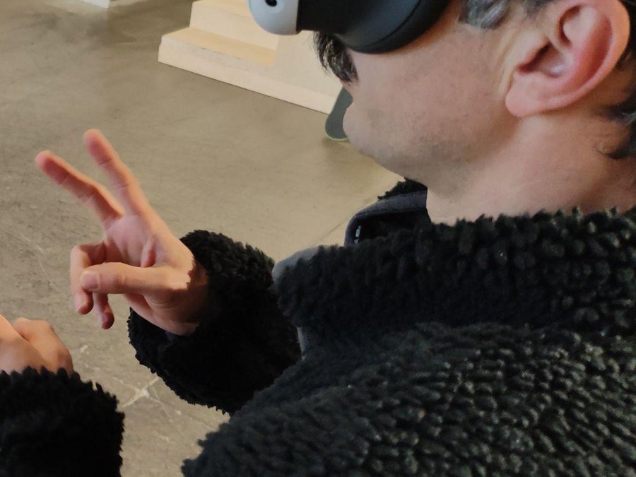 A person wearing an XR headset forming a sign language gesture