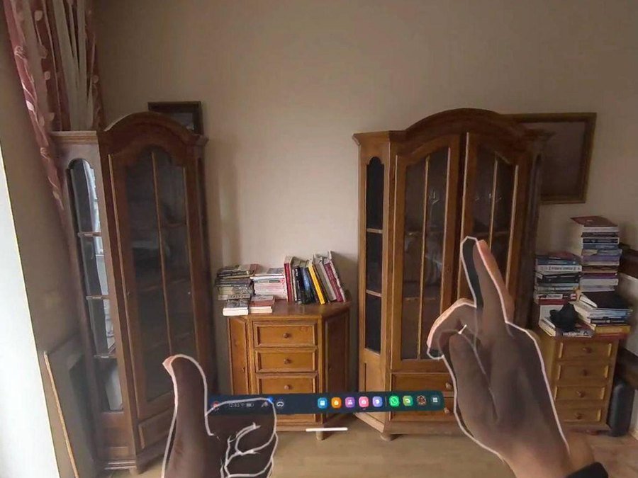 A passthrough view of a room with both hands signing in the foreground